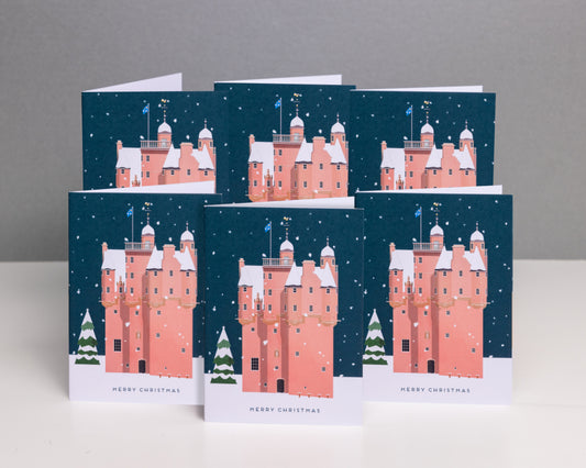 A stack of Christmas cards featuring an illustration of Craigievar Castle with a snowy backdrop and the text 'Merry Christmas' visible on the front.
