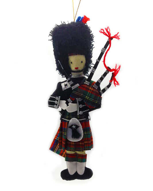 Decorative ornament of a Scottish bagpiper in traditional attire on a white background