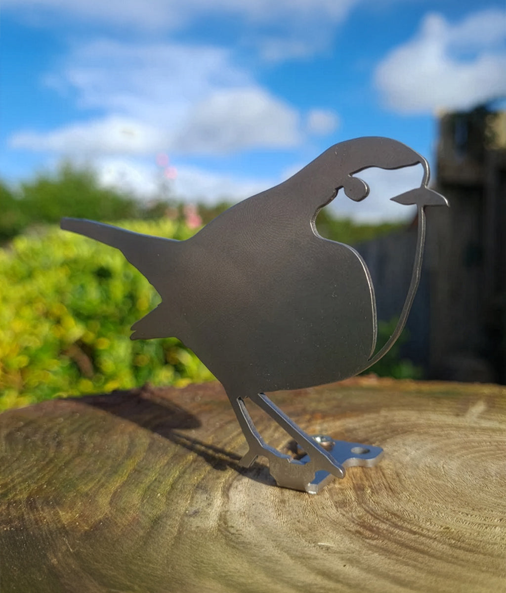 Metal robin sculpture on a wooden log with a blurred natural background