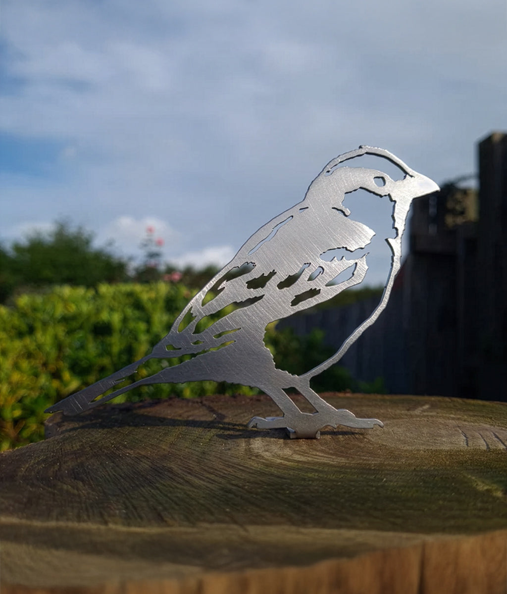 Metal Sparrow Fence Topper sculpture on a wooden post with a blurred natural background