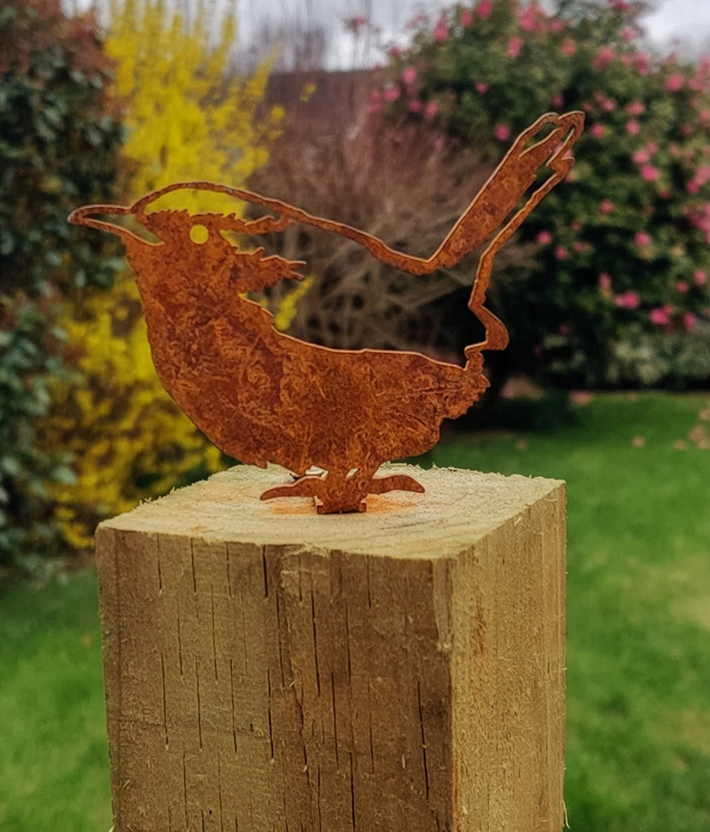 Rusted Wren Fence Topper metal bird sculpture on a wooden post with a garden background