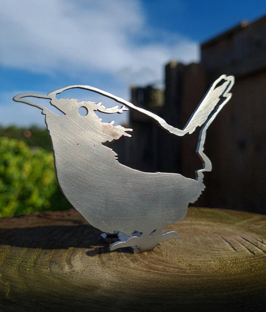 Wren Fence Topper sculpture on a wooden surface with a blurred natural background