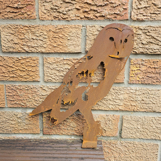 Rust-colored metal owl sculpture on a brick wall