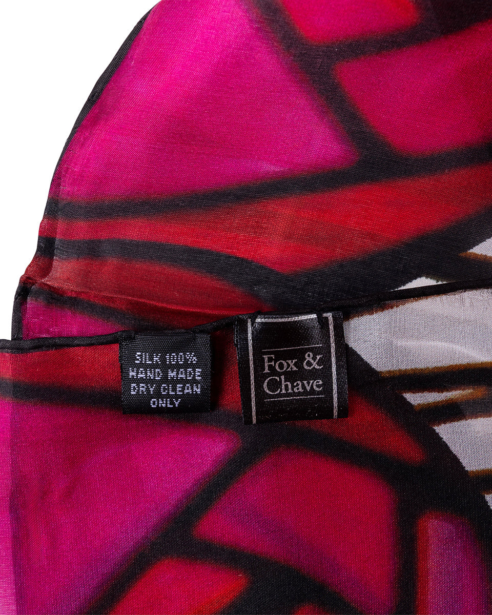 Close-up of a pink and black patterned chiffon scarf with a Fox & Chave label.