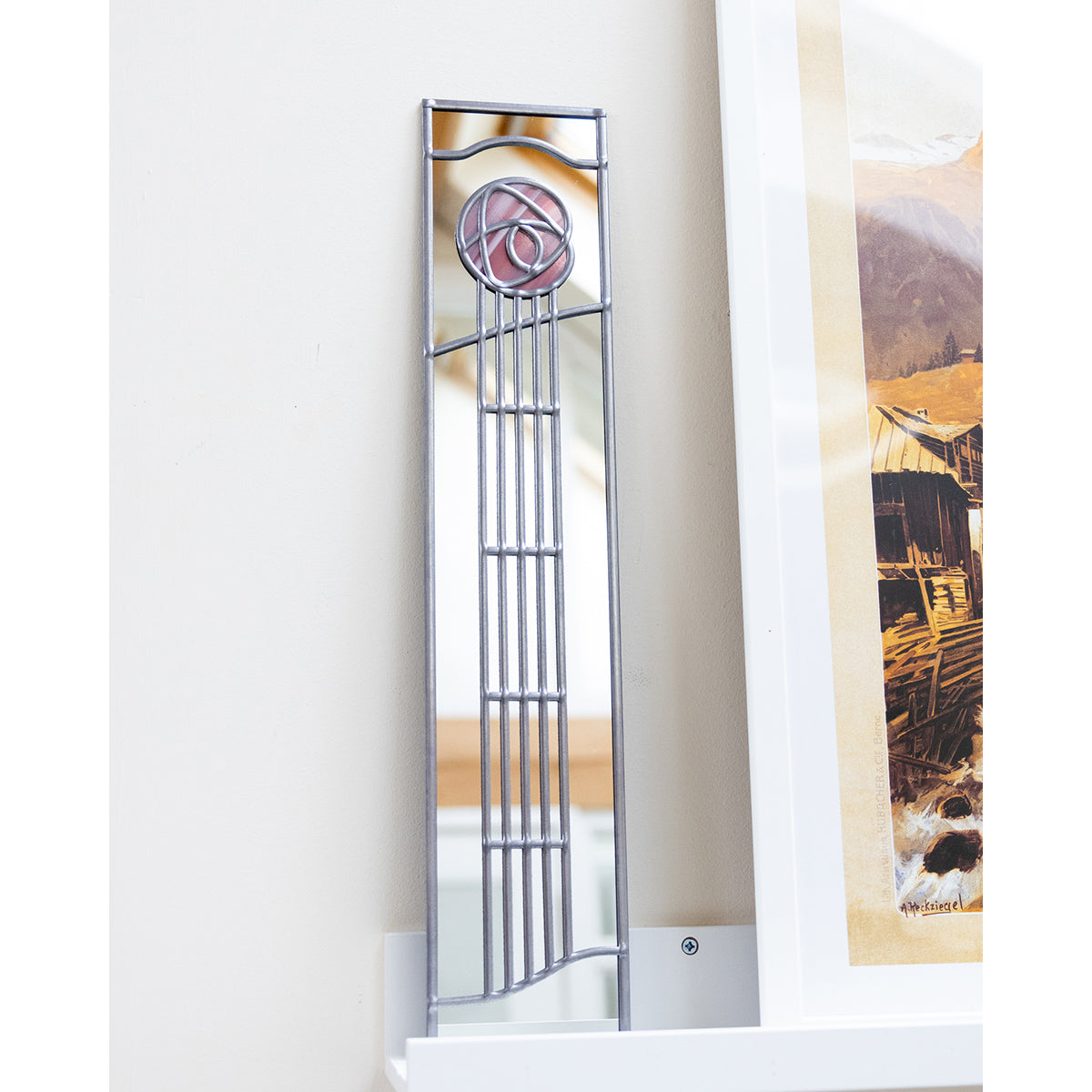 Tall vertical mirror with decorative frame on a white wall