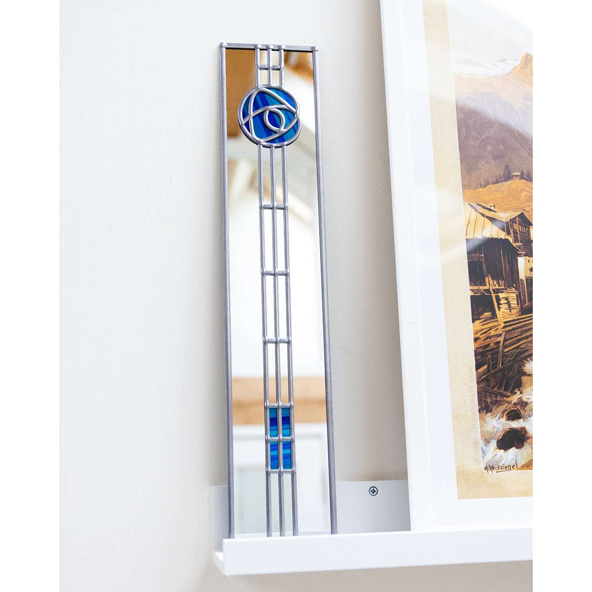 Decorative mirror with a blue circular design on a white wall