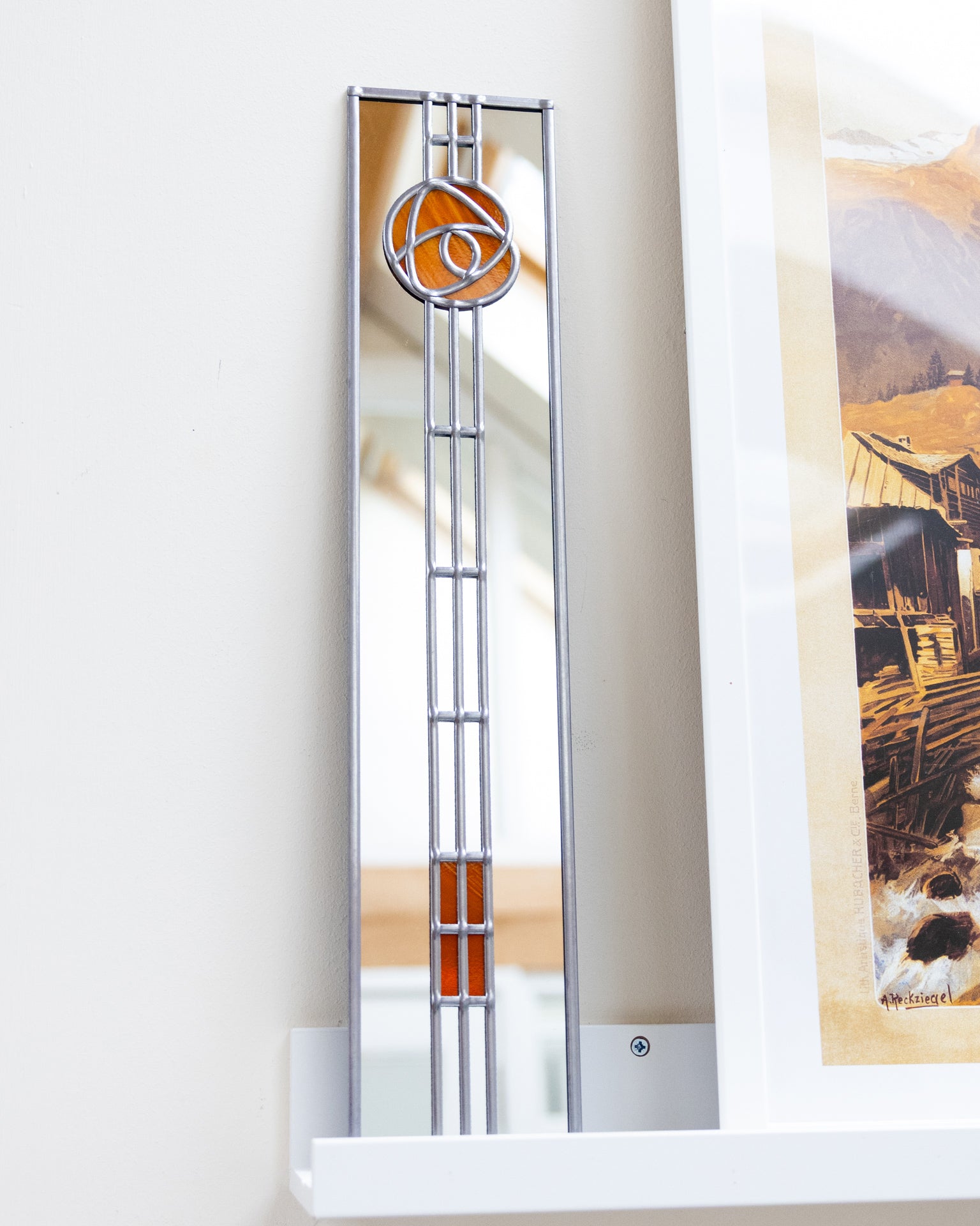 Decorative mirror with a geometric design on a white wall