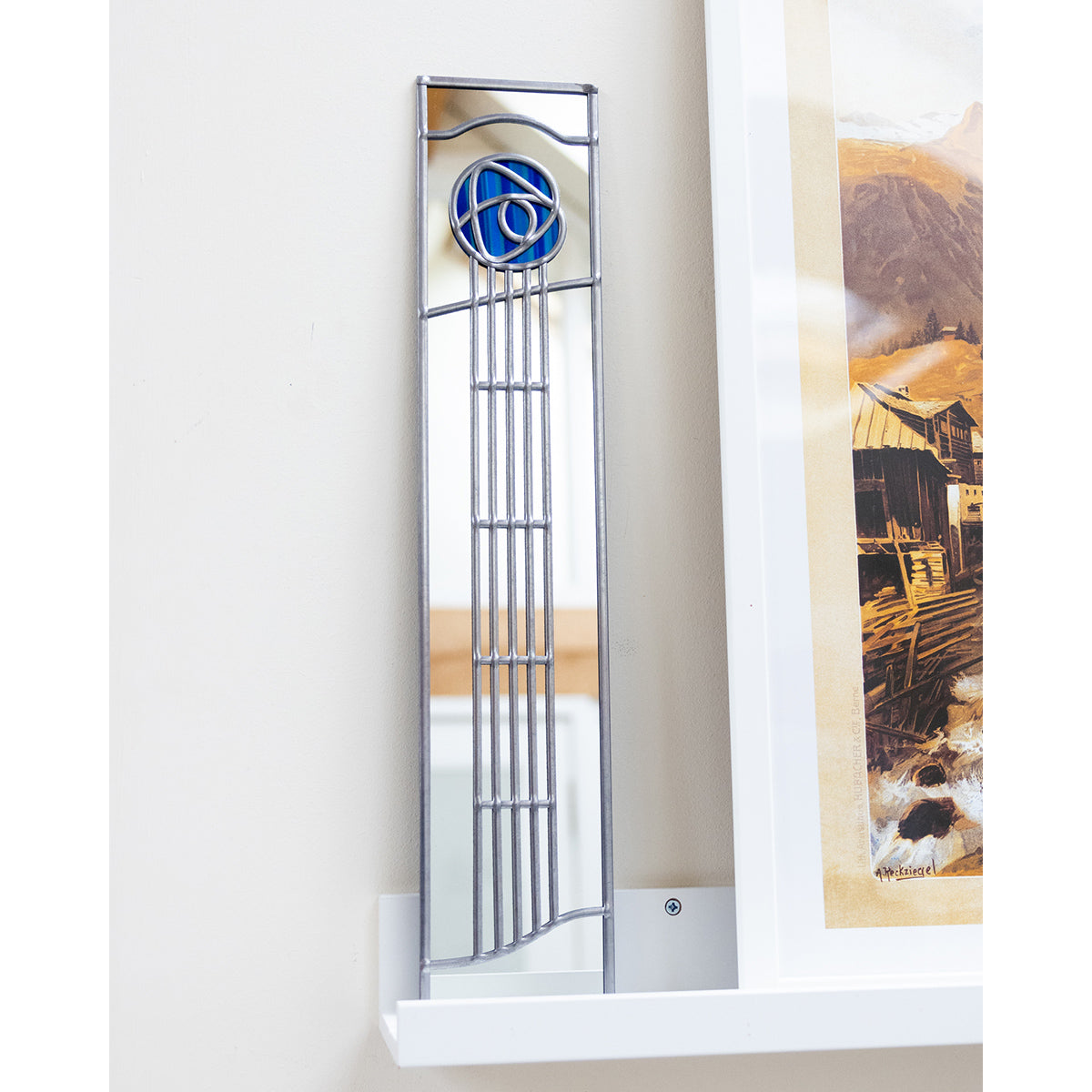 Tall narrow mirror with decorative frame on a white wall