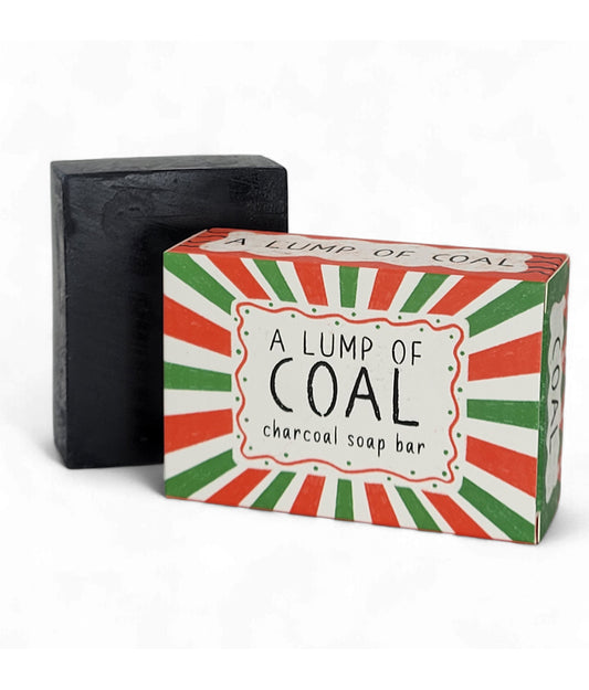 Black charcoal soap bar next to its colorful packaging on a white background