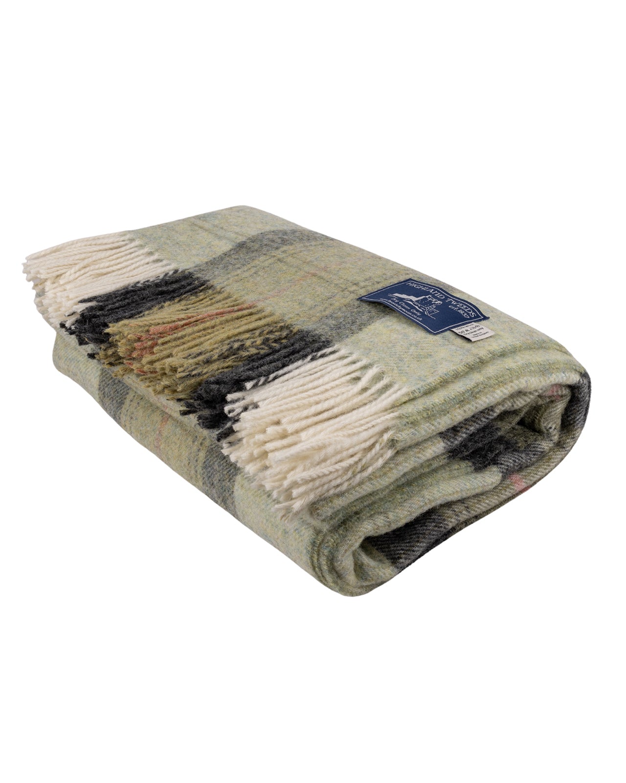 A folded Skye Green Pure New Wool Throw Blanket with cream fringe, featuring a mix of sage green, gray, black, and beige tones, with a small blue brand label.