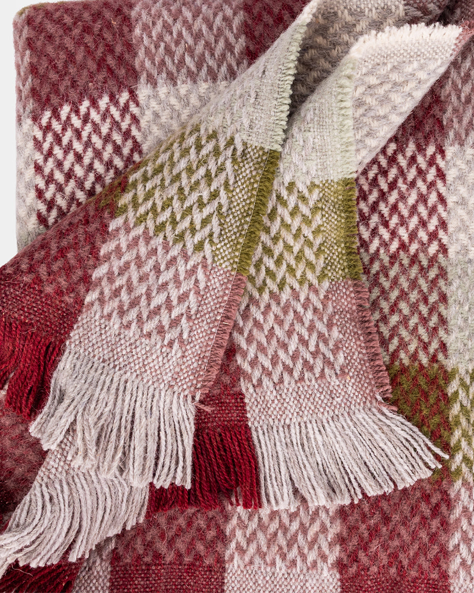Close-up of a plaid blanket with red, green, and white patterns.