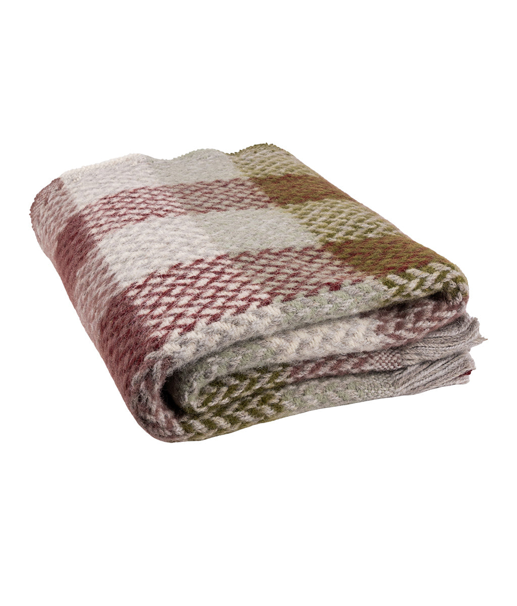 Folded plaid blanket with red, green, and beige colors on a white background