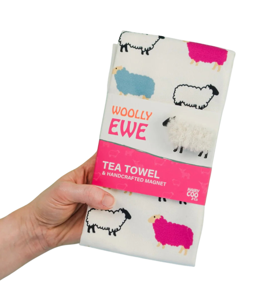 Tea towel with sheep design held by a hand, branded 'Woolly Ewe'.