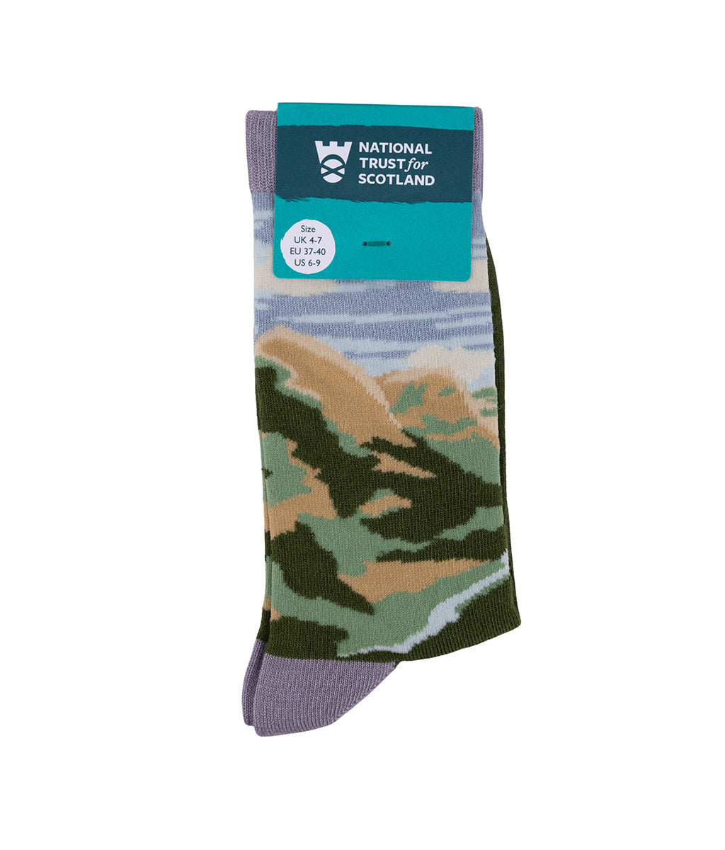 Pair of socks with a Glencoe landscape design on a white background with National Trust for Scotland packaging