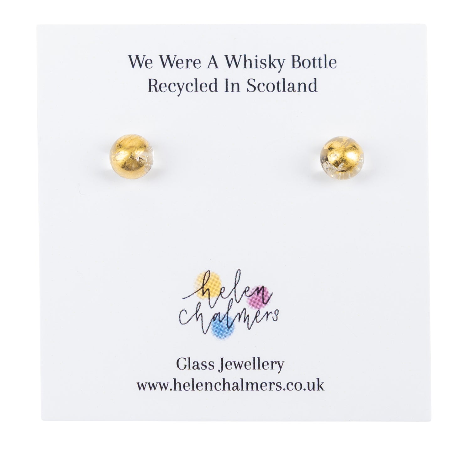 A pair of recycled whisky bottle clear glass and gold stud earrings displayed on a white backing card. The card reads 'We Were A Whisky Bottle Recycled In Scotland' and shows the Helen Chalmers glass jewellery branding.