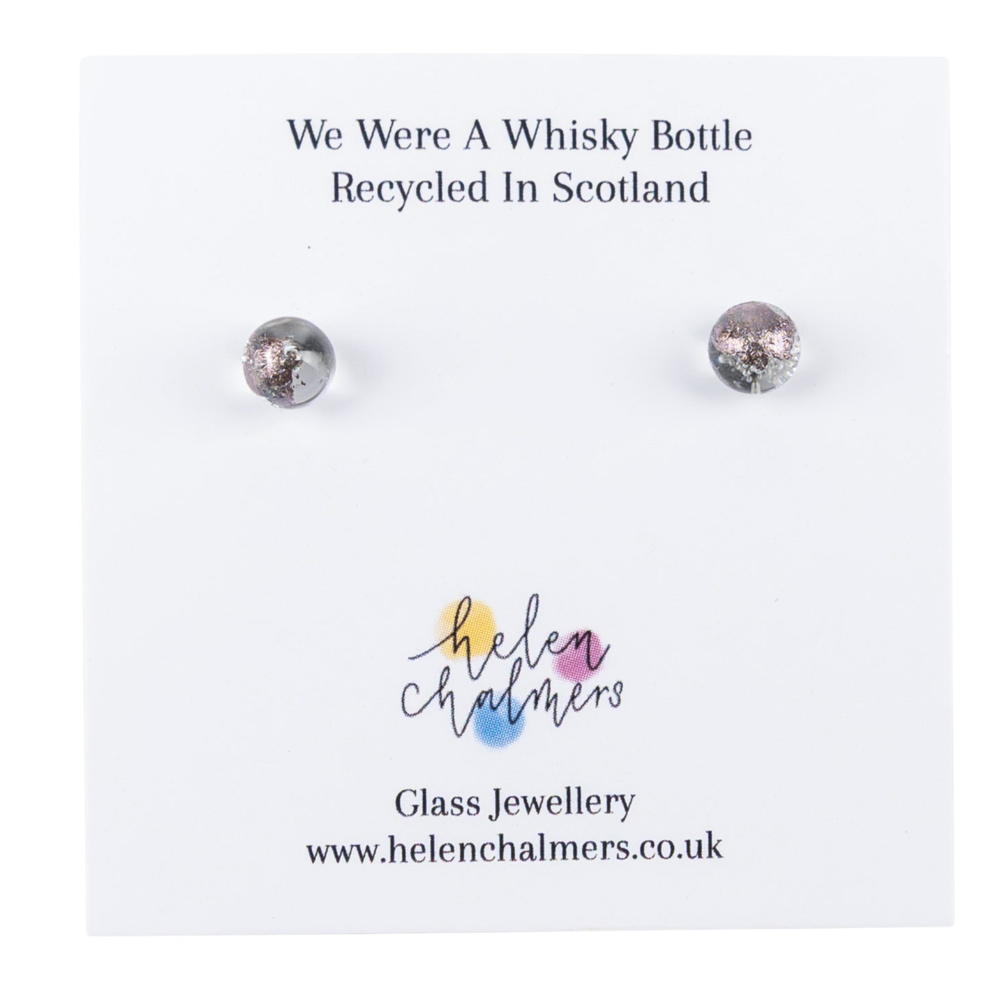 A pair of recycled whisky bottle clear glass and palladium stud earrings, displayed on a white branded backing card that reads 'We Were A Whisky Bottle Recycled In Scotland' and shows the Helen Chalmers logo.