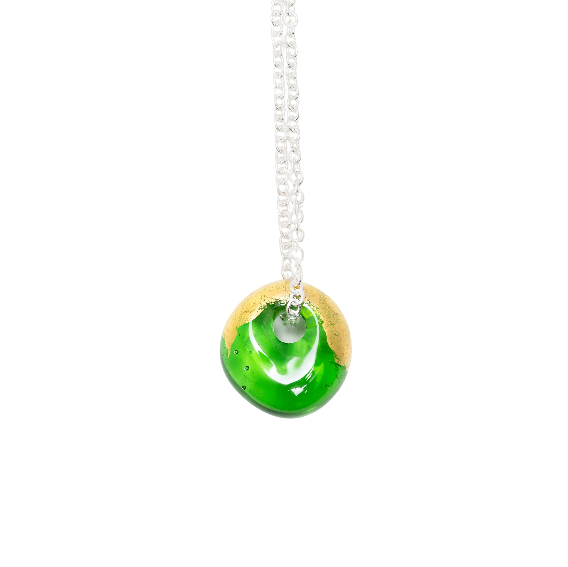 A round glass pendant necklace with a vibrant green and gold design, suspended from a silver chain against a plain white background.