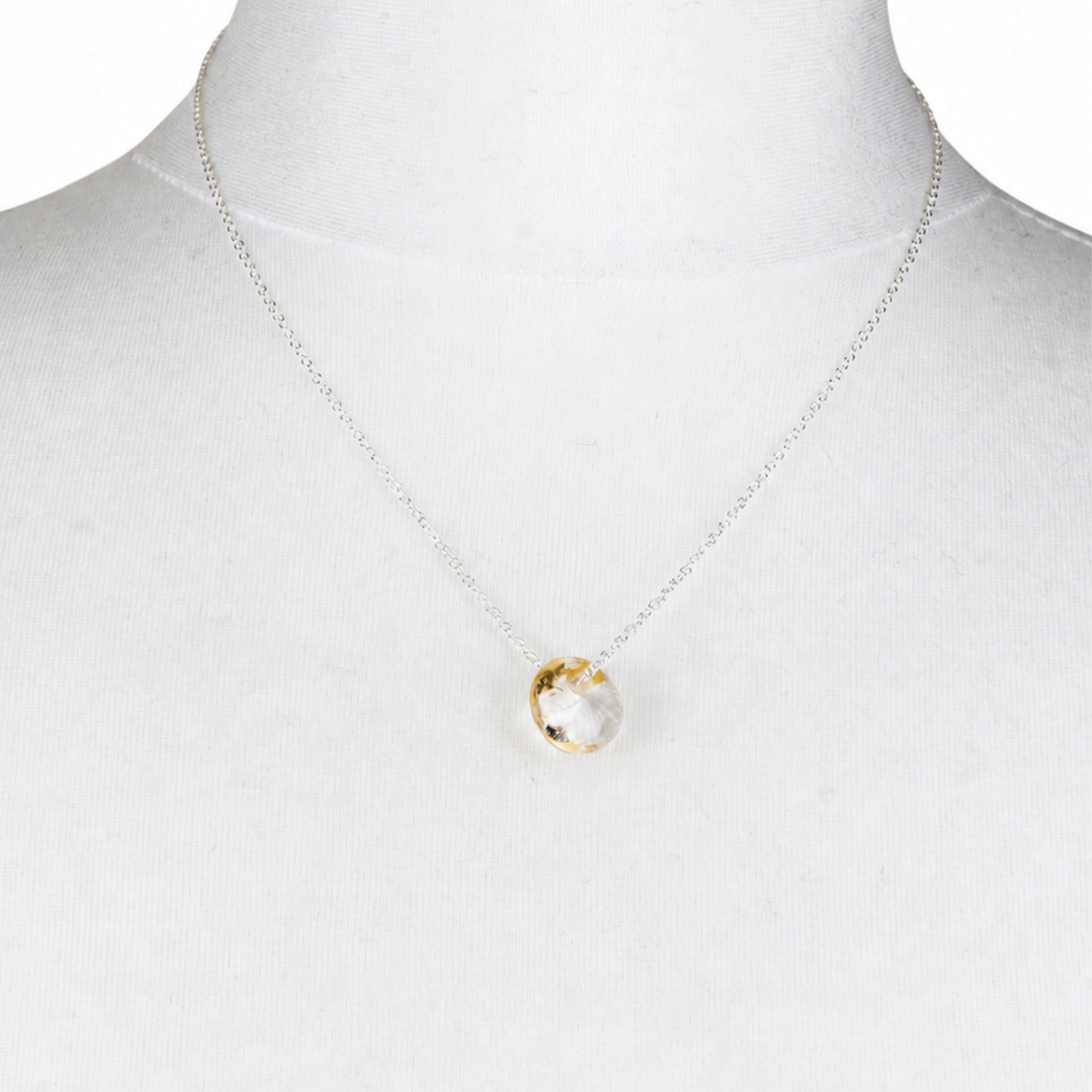 A delicate recycled whisky bottle clear glass and gold pendant, displayed on a white mannequin bust.