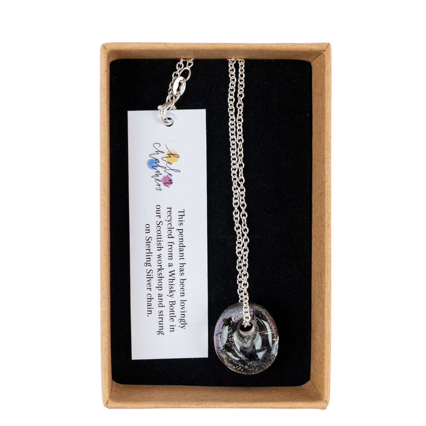 A recycled whisky bottle clear glass and palladium pendant, presented in a brown cardboard gift box with a black interior and a white product tag.