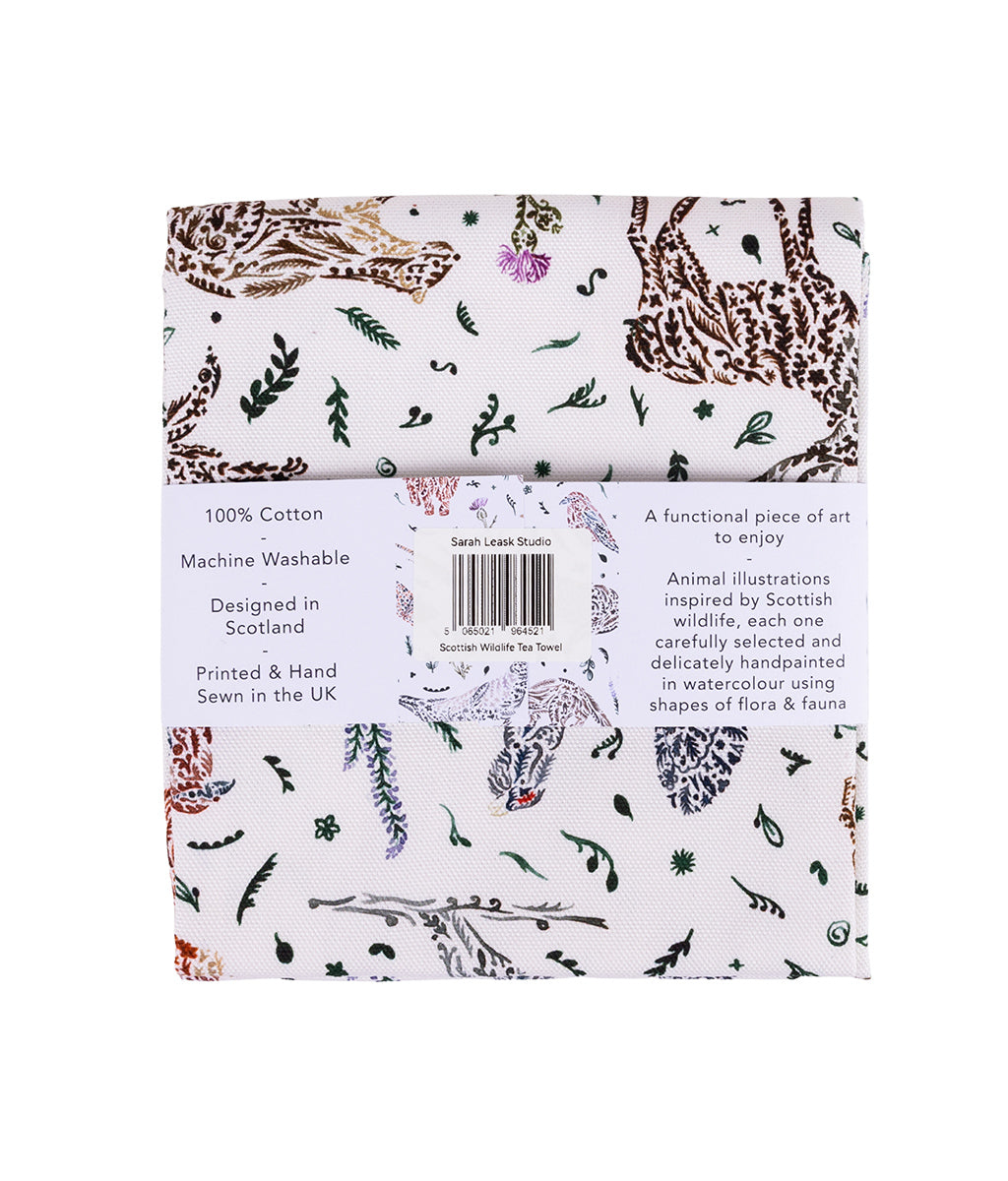 Packaged Wildlife Tea Towel by Sarah Leask featuring patterned fabric with animals and plants on a white background