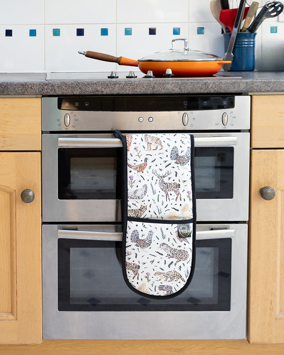 Scottish Wildlife Oven Gloves by Sarak Leask hanging on an oven door