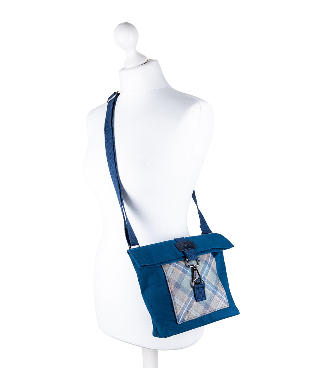 Blue crossbody bag with plaid pocket on a mannequin against a white background