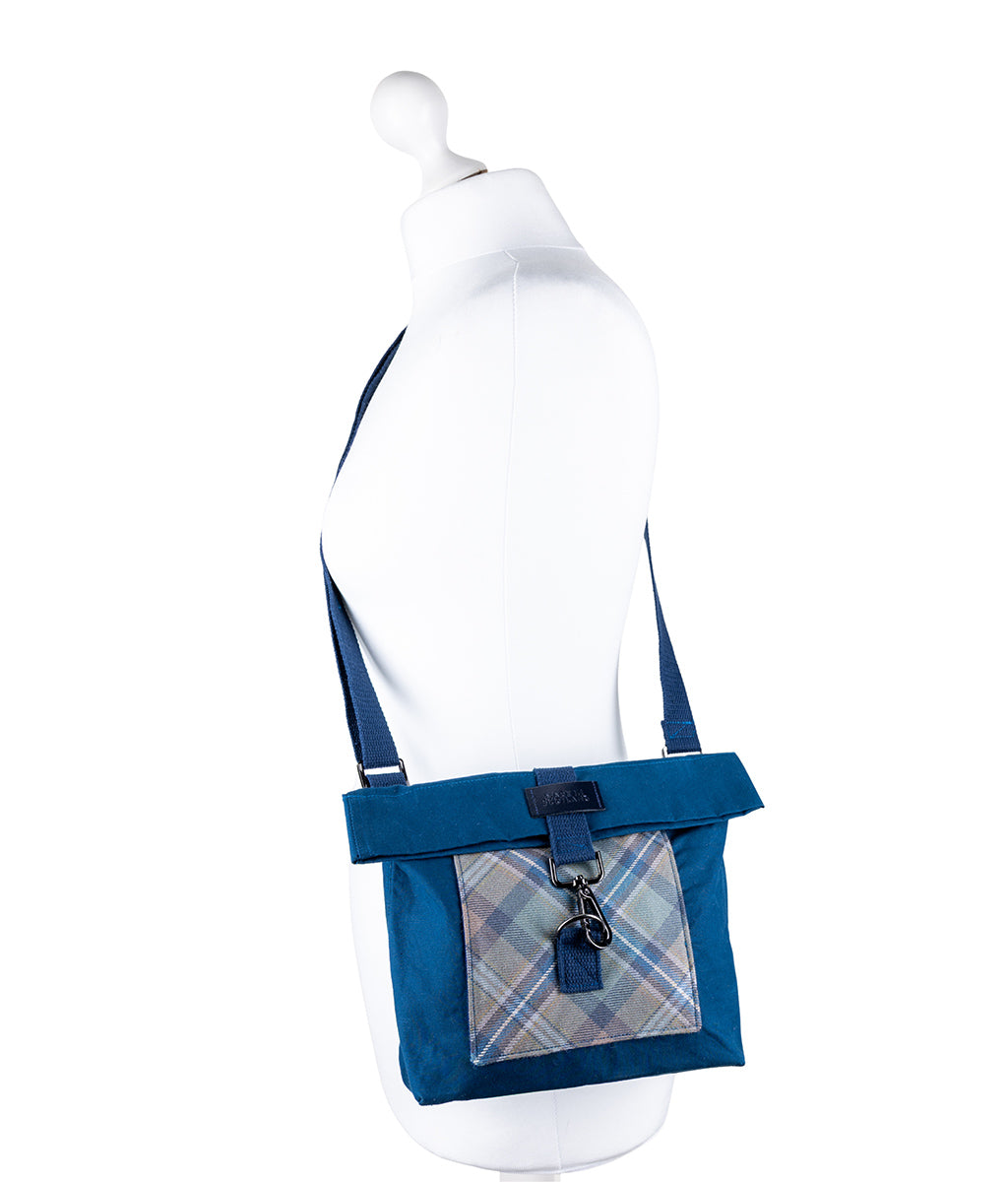 Blue crossbody bag with plaid pocket on a mannequin against a white background