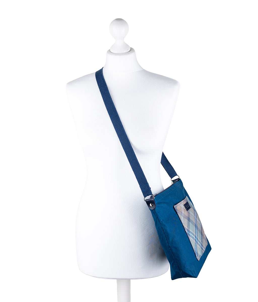Blue crossbody bag on a mannequin against a white background
