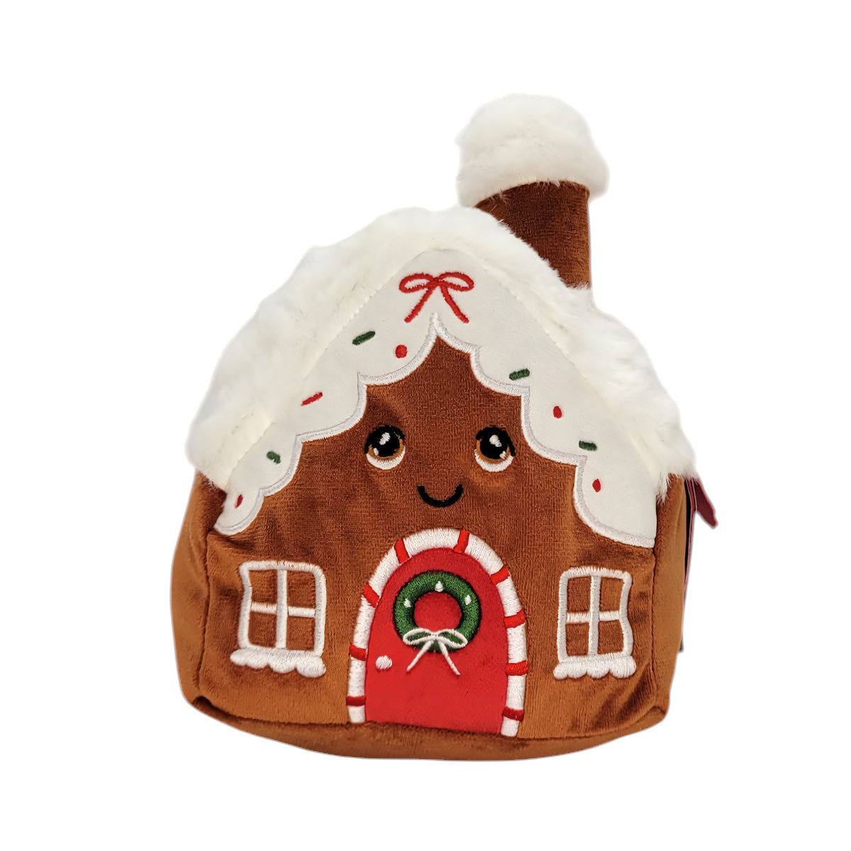 A gingerbread house plush toy with a smiling face, white faux-fur roof and chimney, red door, and green wreath on a plain white background.
