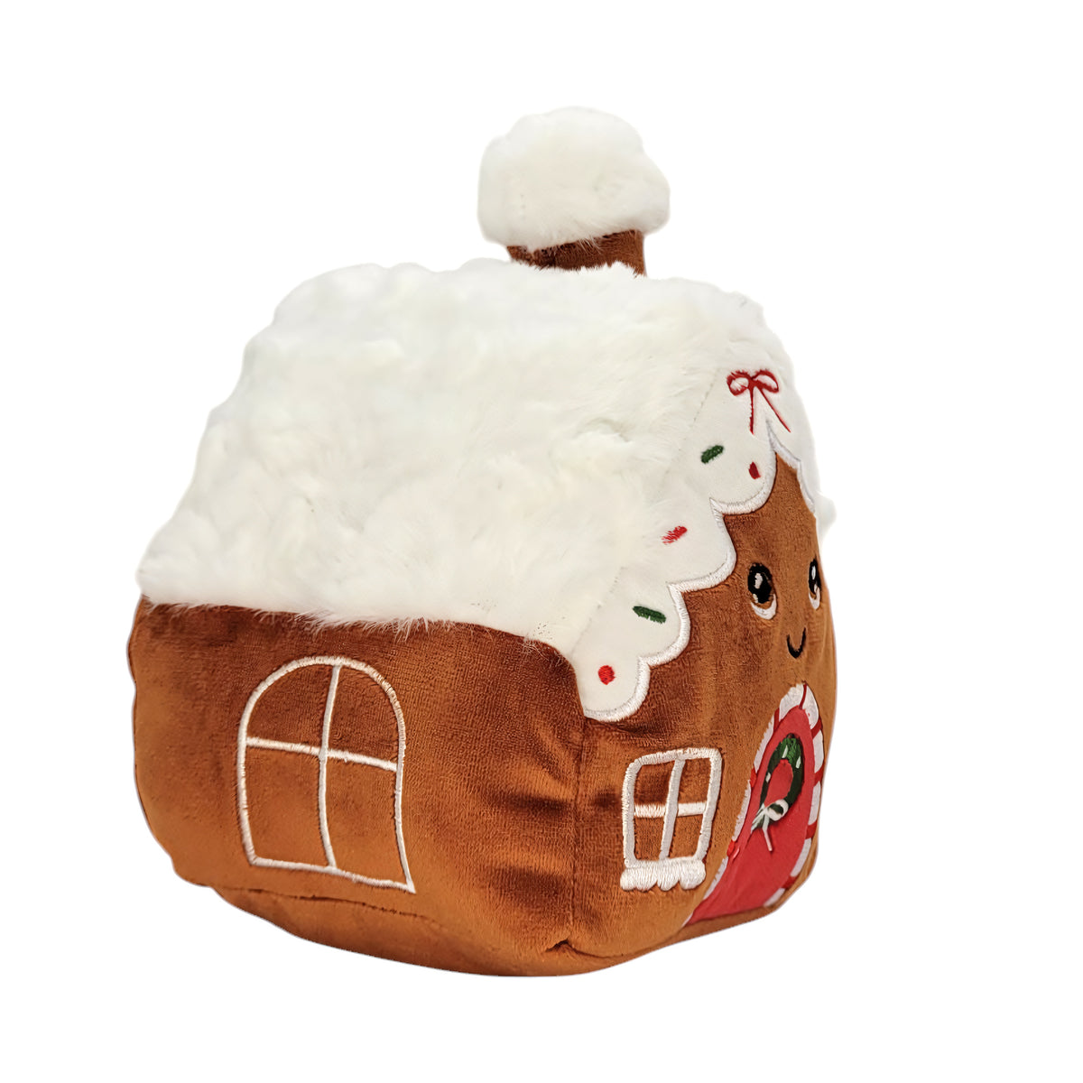 A gingerbread house plushtoy with a white faux-fur roof, brown fabric body, embroidered windows, and a smiling face on the side.
