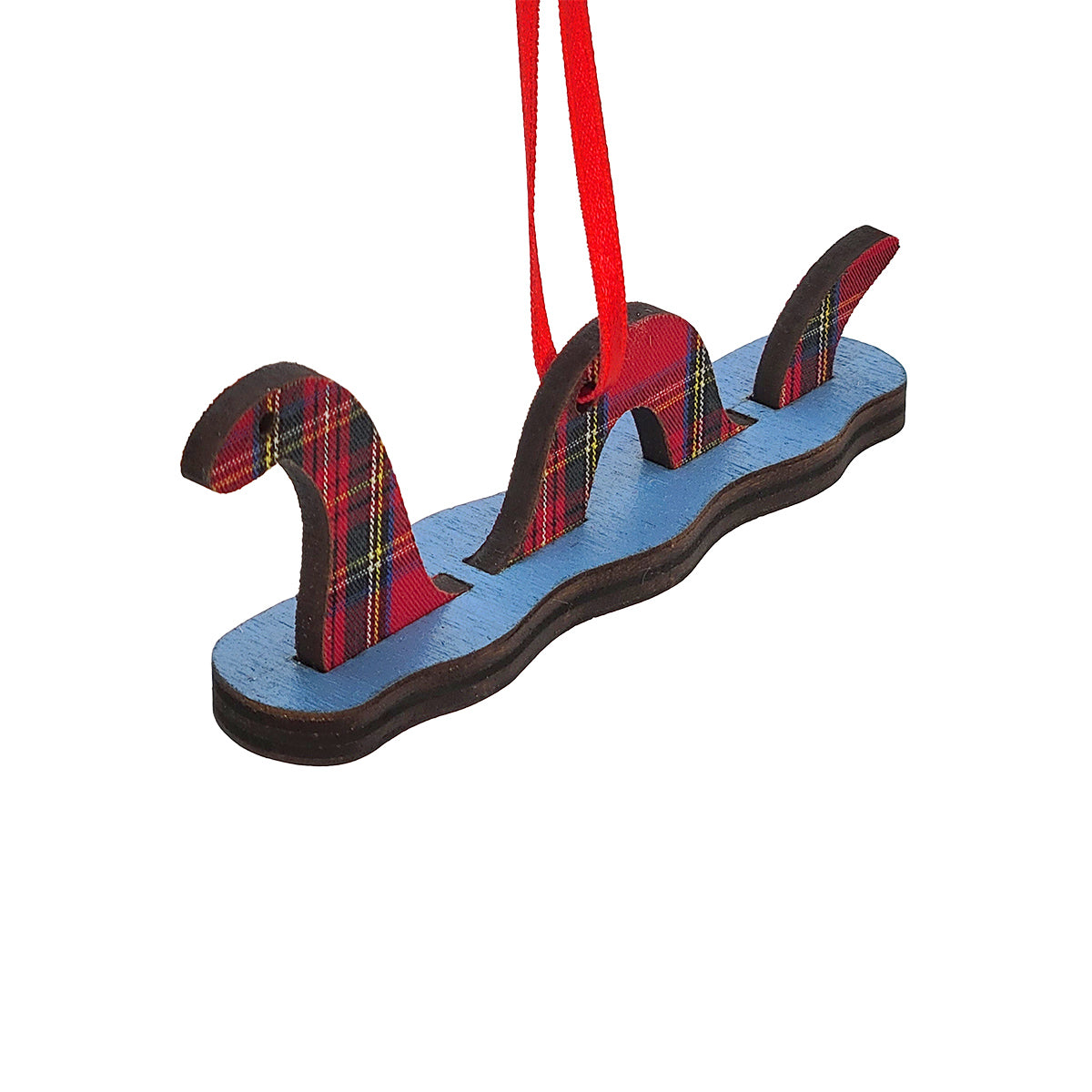A Scottish Highlands 'Loch Ness' monster Christmas ornament made of layered wood with a red tartan plaid pattern and a red hanging ribbon, shown on a plain white background.
