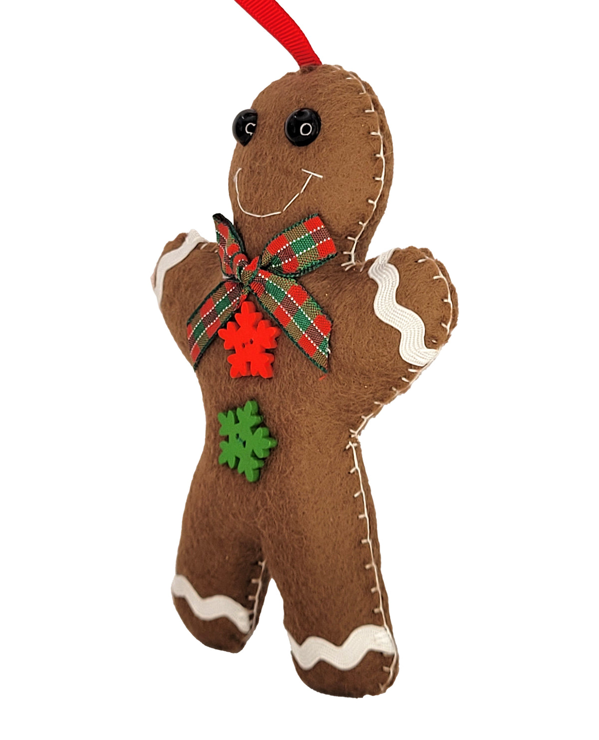 A brown felt gingerbread man Christmas ornament with white icing details, a red and green plaid bow, a red felt snowflake, and a green felt snowflake on the chest, hanging from a red ribbon.