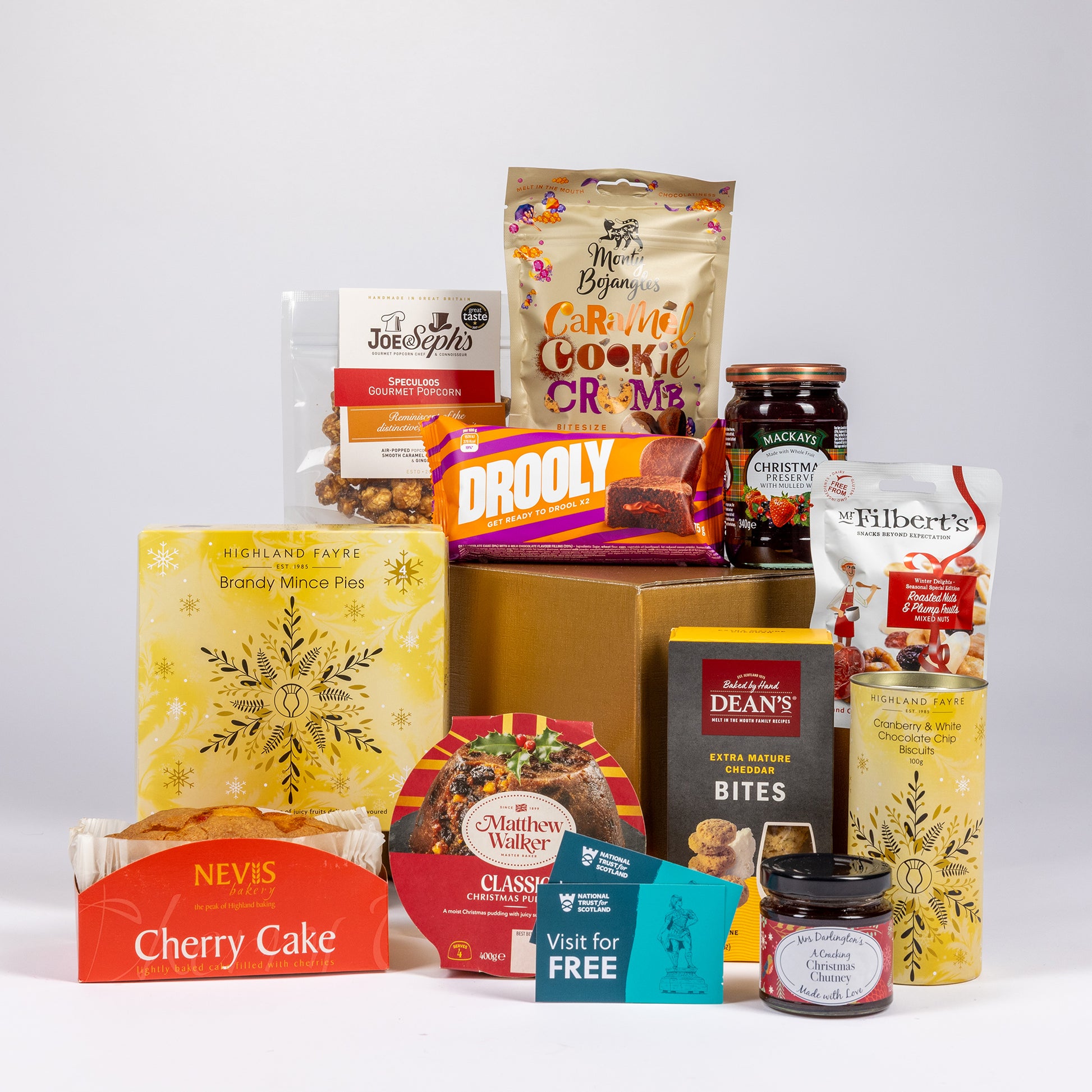 A curated Christmas hamper bundle of assorted treats and snacks arranged on a light gray studio background.