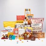 A curated snack and candy gift assortment arranged on a light gray studio background.