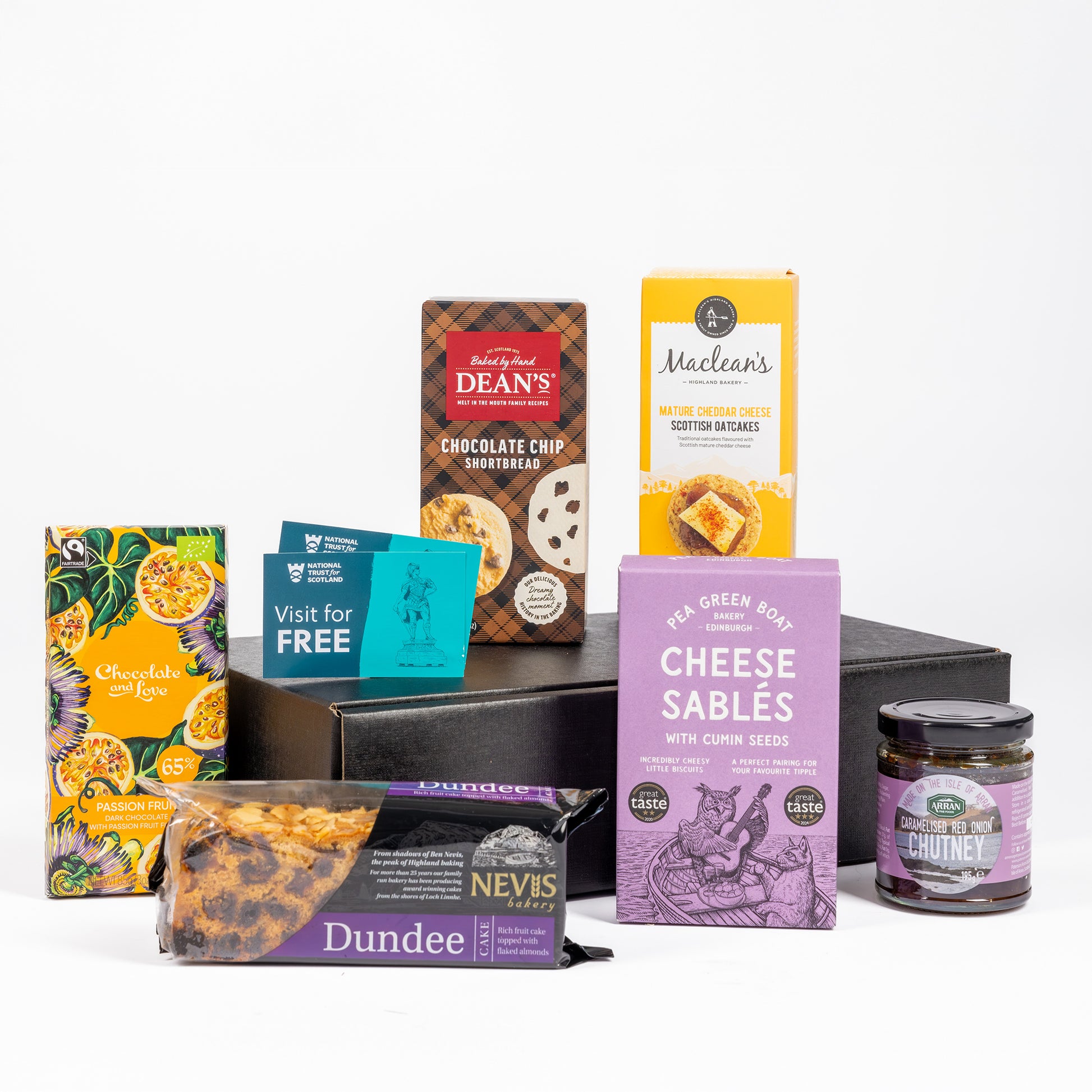 A curated gift basket of assorted Scottish snacks and treats arranged on a black tray against a white background. 