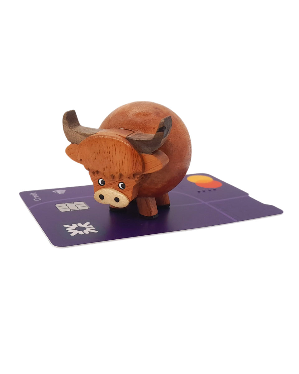 Small Wooden Highland Cow Ornament sitting on a credit card