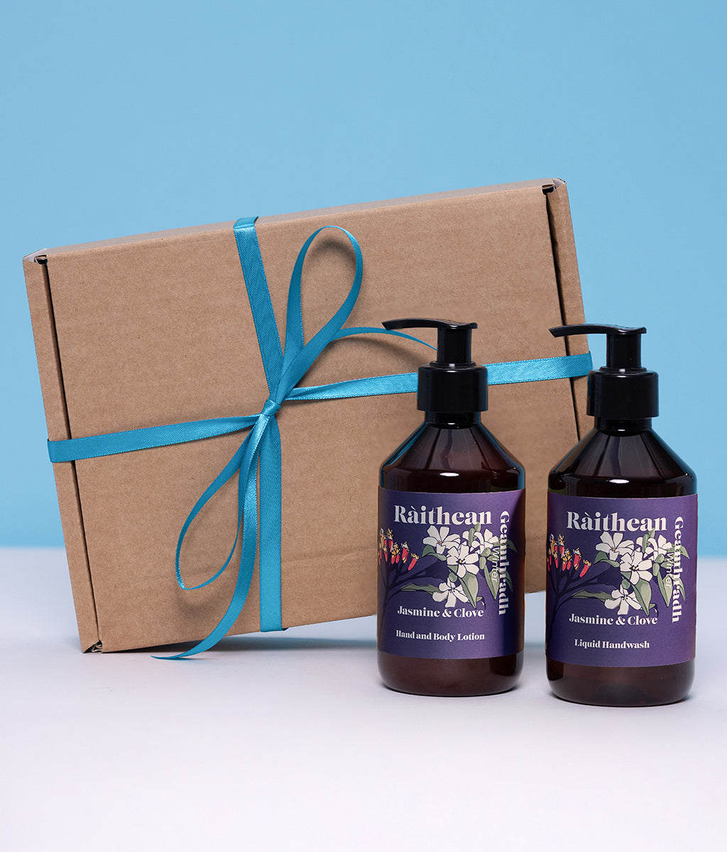 Two bottles of Raithean Winter Jasmine & Clove product with a brown box tied with teal ribbon on a light blue background.