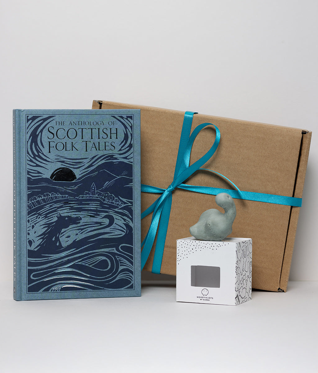 Book titled 'The Anthology of Scottish Folk Tales' with a wrapped gift and small figurine on a white background