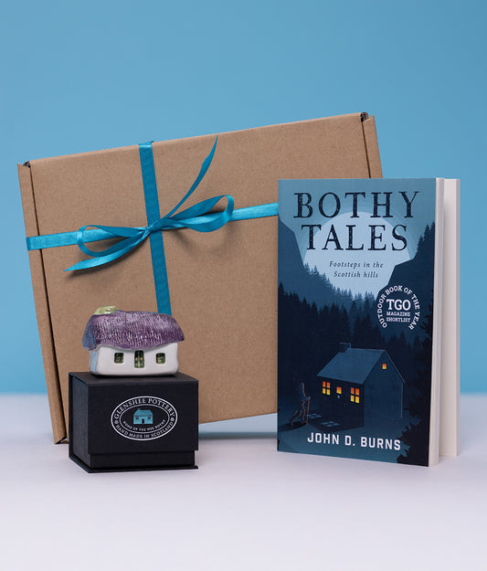Book titled 'Bothy Tales' by John D. Burns with a small house-shaped object and a cardboard box on a blue background