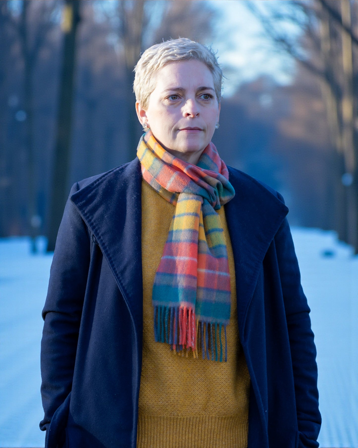 Person wearing a colourful Antique Buchanan Tartan Lambswool Scarf and dark coat in a snowy landscape