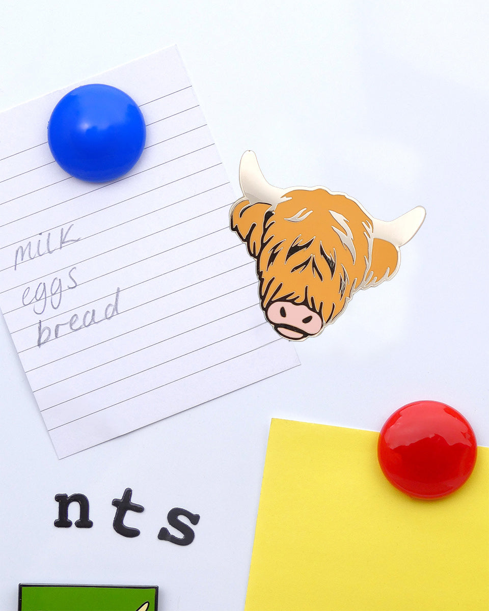 Educational materials with a cow magnet, magnetic letters, and a piece of paper on a white background.