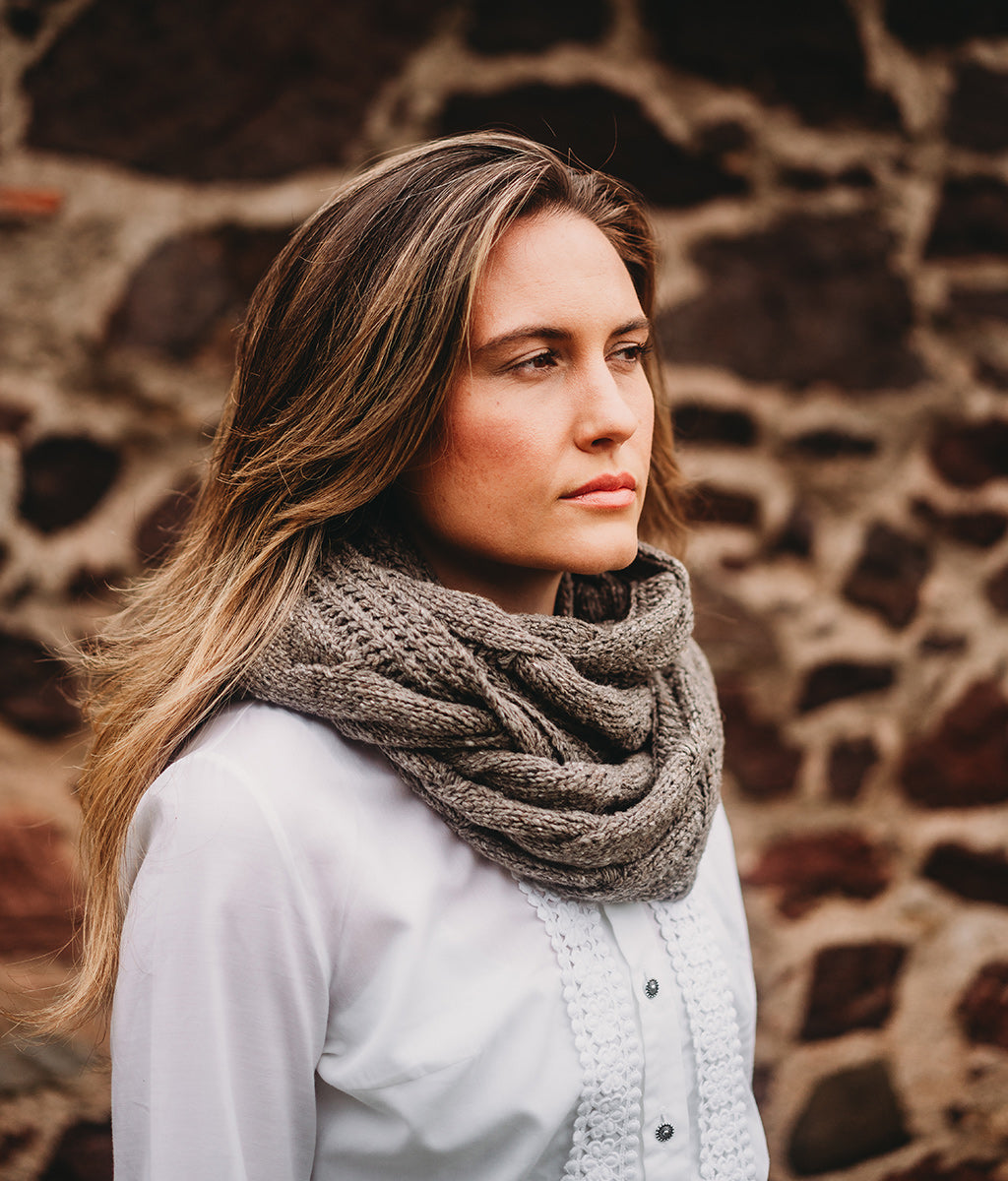 Woman wearing a large knitted Merino Wool Rhennish Cowl against a stone wall background