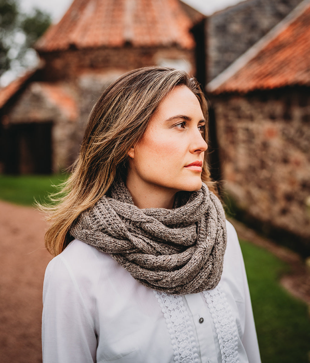 Woman wearing a large knitted Merino Wool Rhennish Cowl against a stone wall background