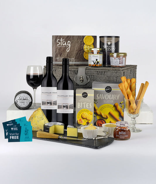 Gourmet gift set with wine, cheese, and snacks on a white background
