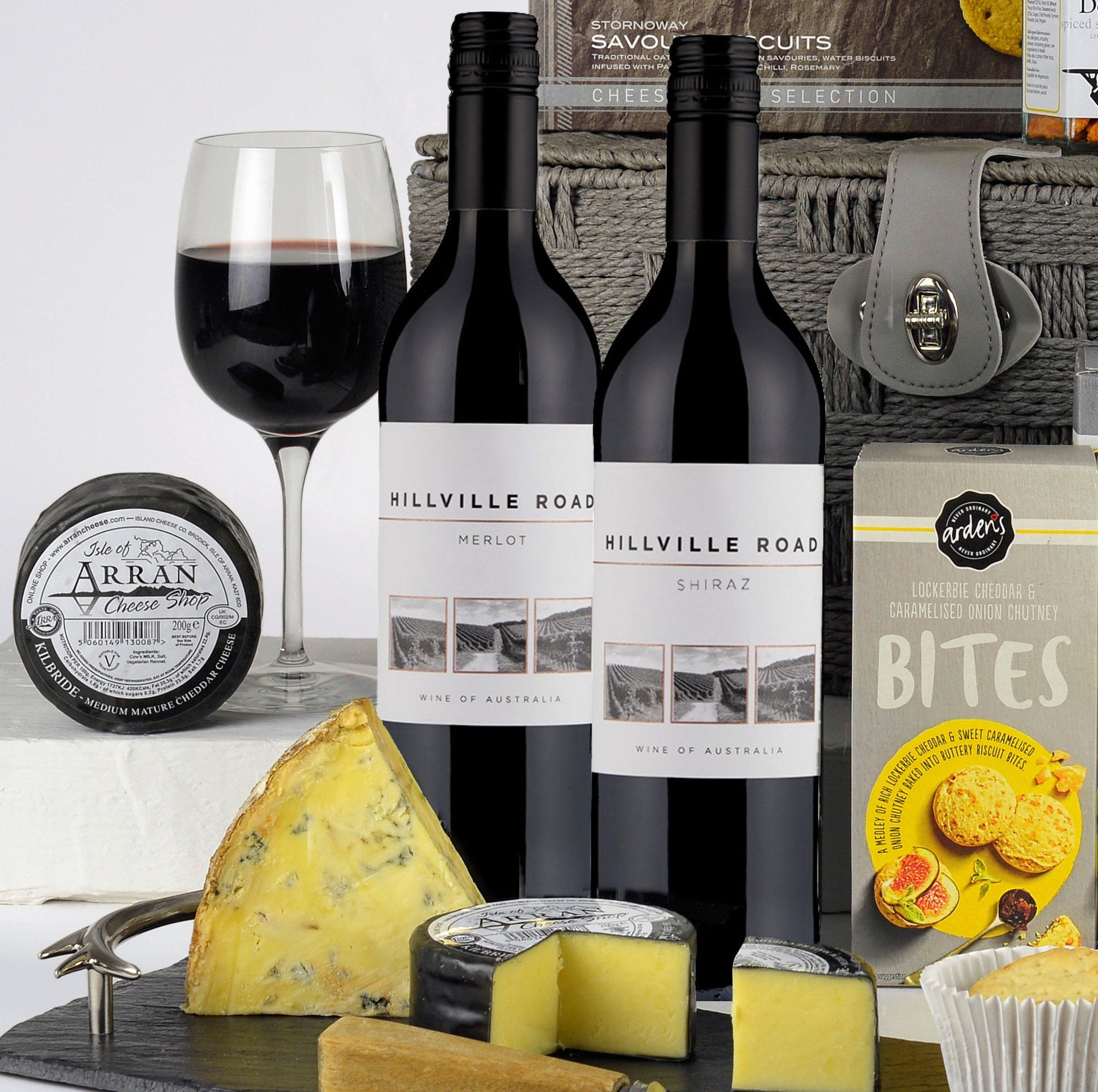 Gourmet gift set with wine, cheese, and snacks on a white background