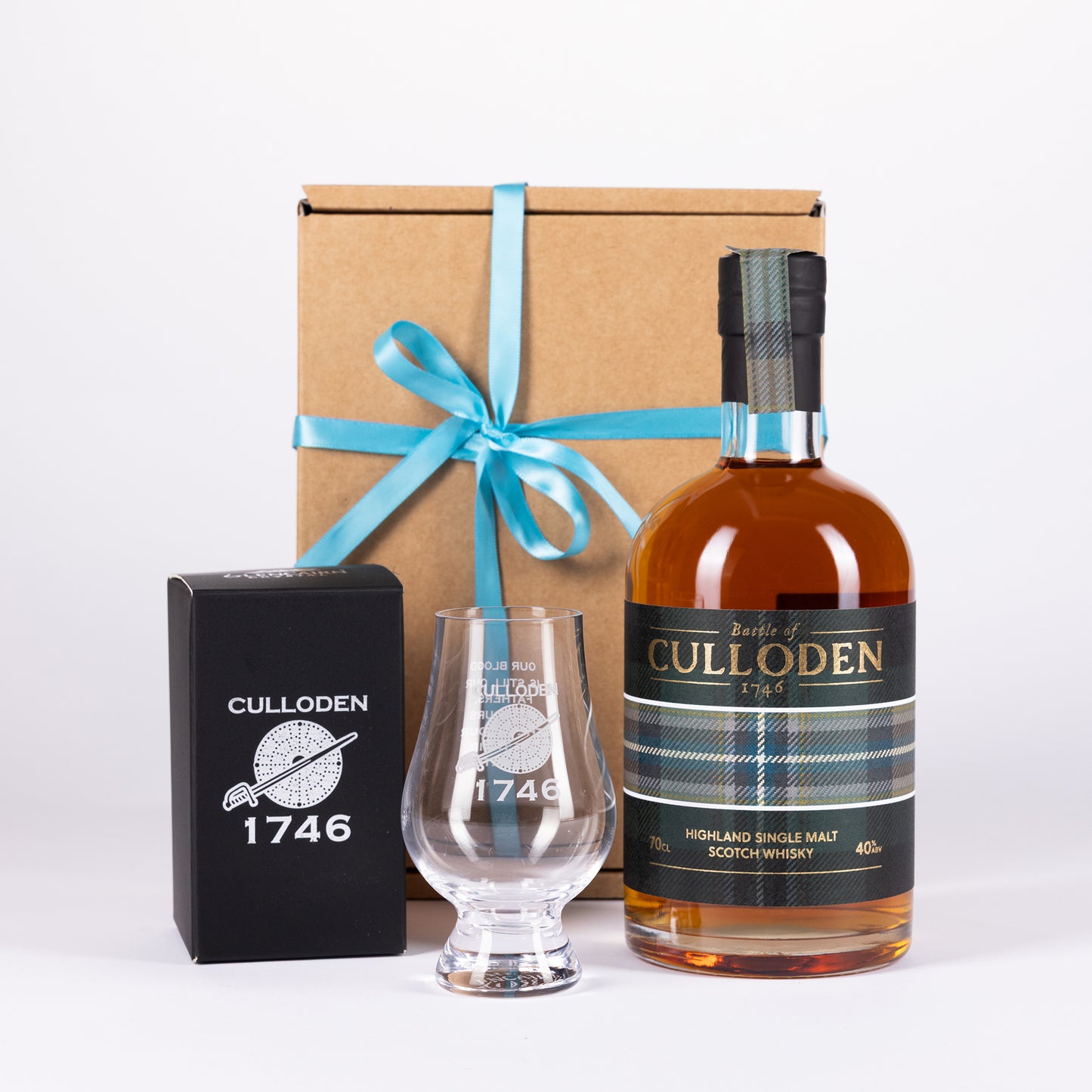 A Culloden 1746 Highland Single Malt Scotch Whisky gift set on a white background, featuring a bottle of amber whisky, a clear etched glass, a black branded box, and a brown gift box tied with a teal ribbon.