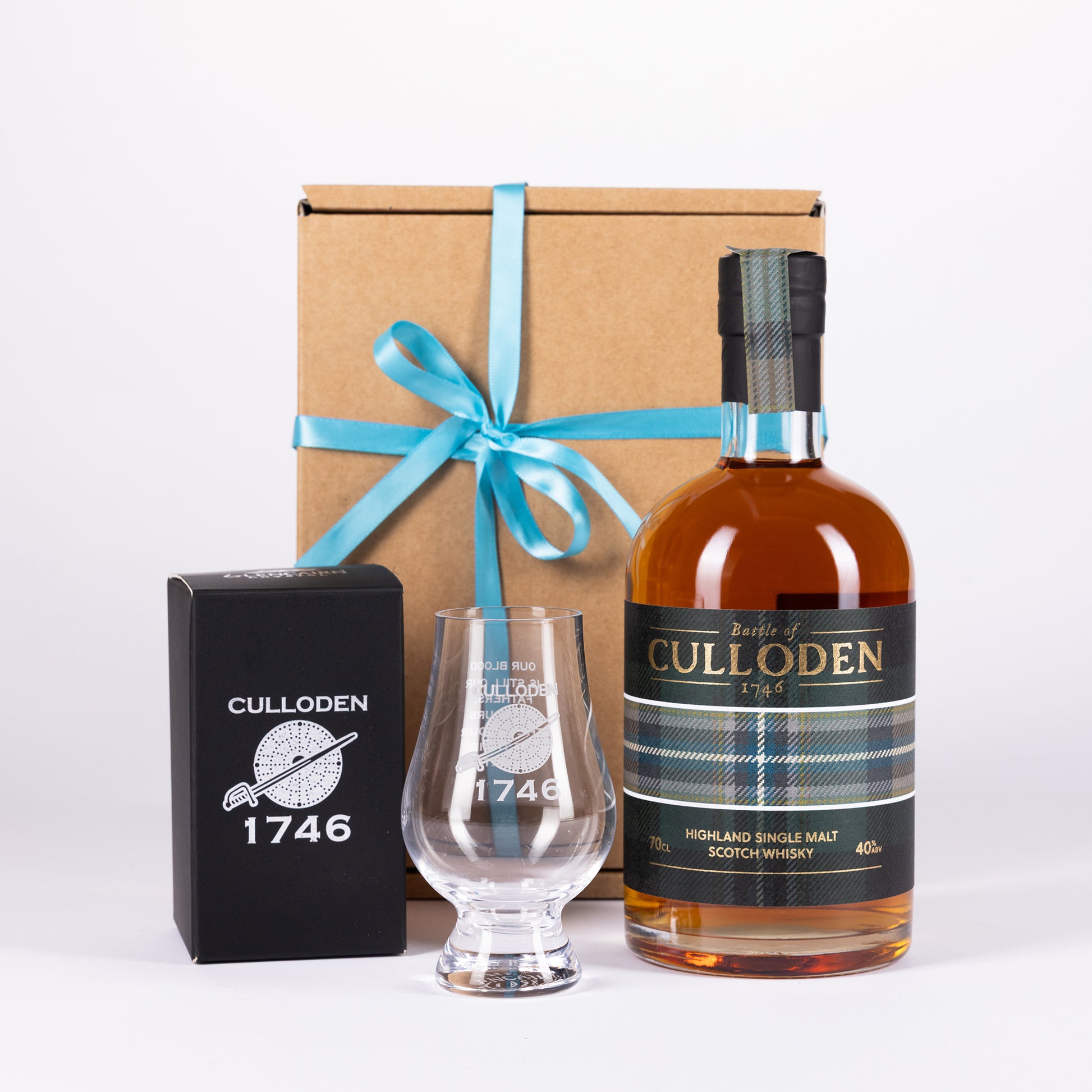 A Culloden 1746 Highland Single Malt Scotch Whisky gift set on a white background, featuring a bottle of amber whisky, a clear etched glass, a black branded box, and a brown gift box tied with a teal ribbon.