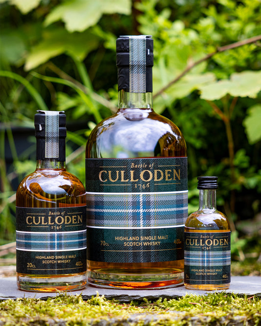 Three bottles of Culloden Highland Single Malt Scotch Whisky on a stone surface with greenery in the background.