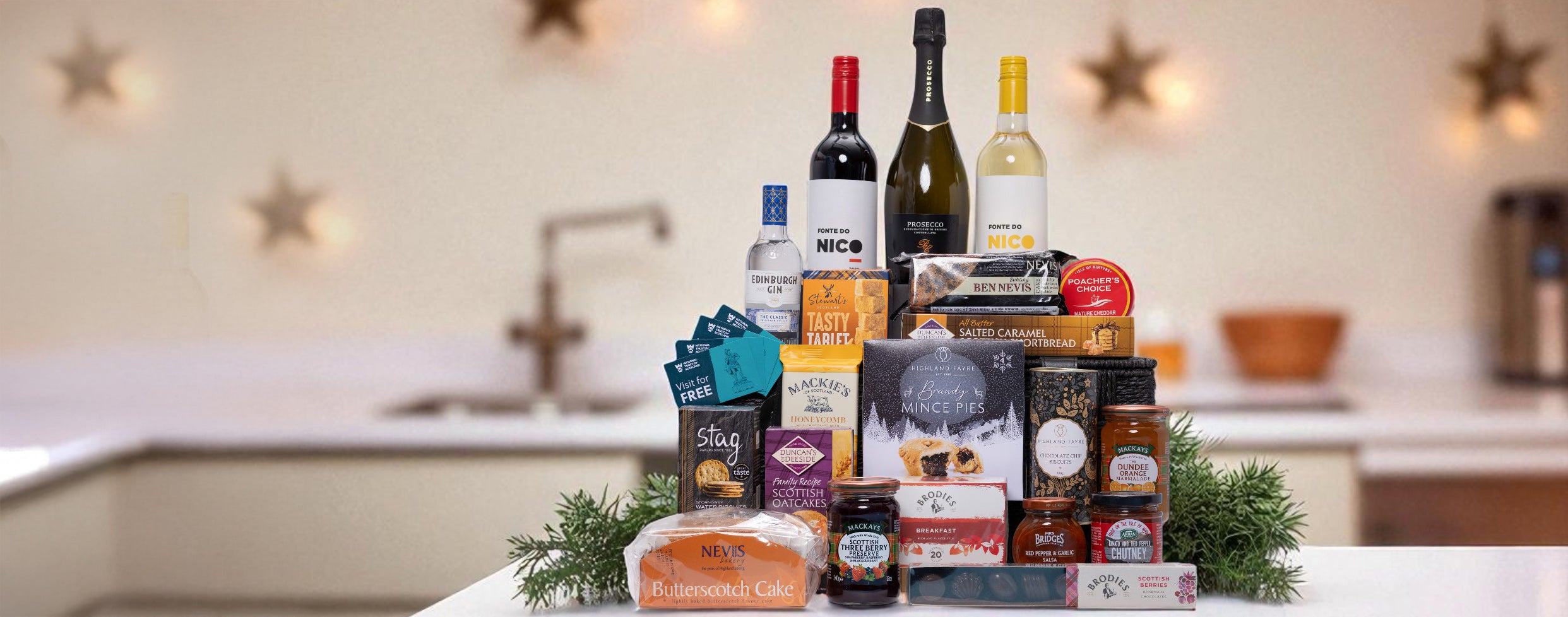 Assorted food and wine products on a kitchen counter with decorative lights in the background.