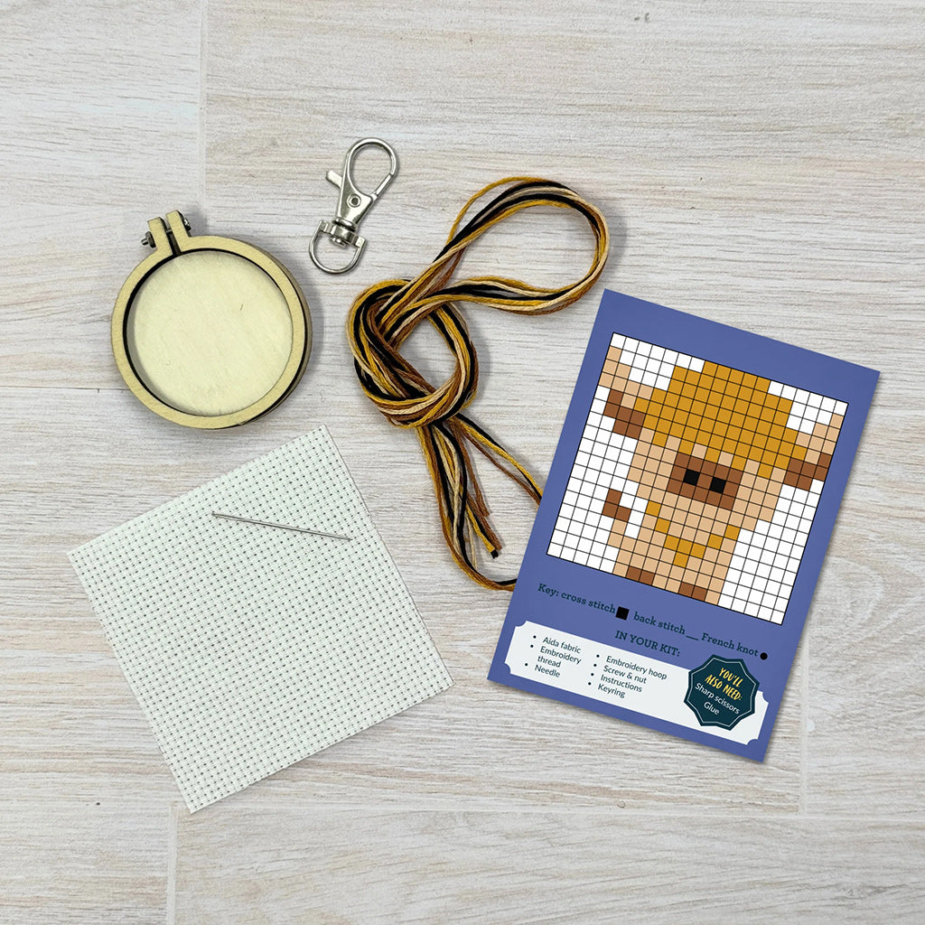 Pixelated dog design on a card with a keychain, lanyard, and white card on a wooden surface.